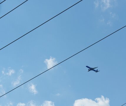 Rows of electric wires and an airplane flying in the skies