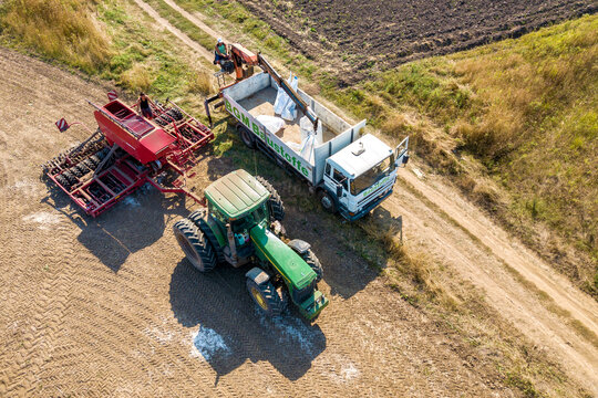 Kyiv, Ukraine - September 17, 2020.Top down aerial view of green tractor cultivating ground and seeding a dry field. Farmer preparing land with seedbed cultivator