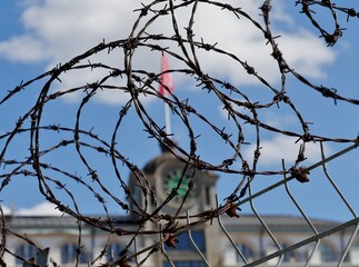 Unscharfes Gebäude hinter Stacheldrahtzaun