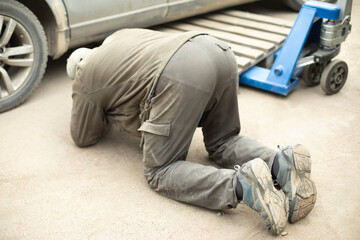 Man looks under car. Wheel replacement. Repair of transport. It's tough task.