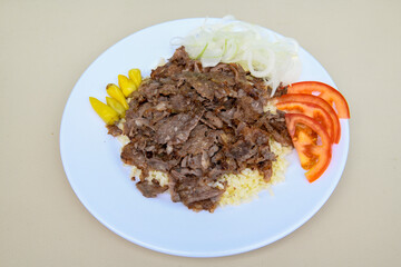 Turkish and Arabic Traditional Ramadan doner kebab with tasty tomato sauce and rice or turkish pilav in white plate on wood table background. ( , Iskender, ekmek arasi pilav ustu doner, doner durum )