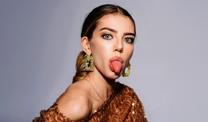 Beautiful girl with bright makeup show tongue. Woman with clean fresh skin and fashionable jewelry.