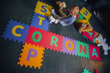 bird view of colorful kids puzzle mat with letters like STOP CORONA and Covid written on them lying...