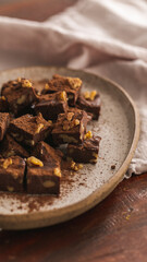 Chocolate fudge on a rustic ceramic , wood surface and linen