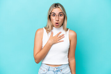 Young caucasian woman isolated on blue background surprised and shocked while looking right