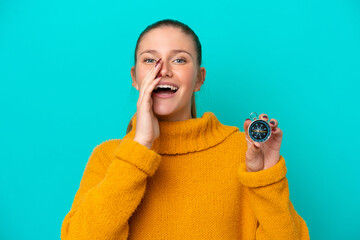 Young caucasian woman holding compass isolated on blue background shouting with mouth wide open