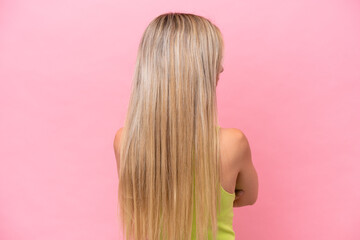 Pretty blonde woman isolated on pink background in back position and looking side