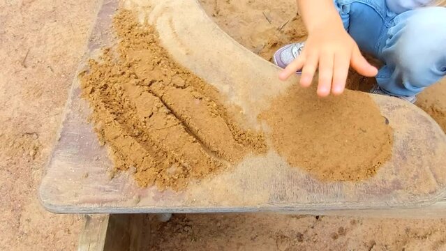 Little girl playing in sand box outdoor. Close up of child hand playing with sand.