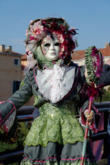Fototapeta na wymiar Venise, Italie, 27 février 2014 : Carnaval de Venise, femme portant une superbe robe verte, masque avec des fleurs, sur le pont du Rialto