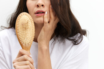 a close horizontal photo of a woman holding a comb with hair inside shockingly opening her mouth. Photo without a face
