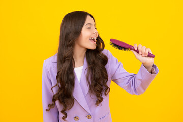 Excited fun teenager girl singing with comb. Child girl with brush combing hair. Girl taking haircare and hairstyle.