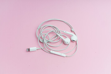 Audífonos blancos sobre fondo rosa.