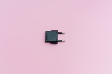 Enchufe adaptador para conector europeo sobre fondo rosa.