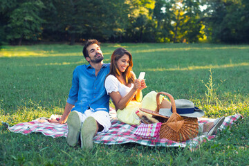 Young smiling couple taking selfie on picnic on the sunny summer meadow