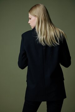 A beautiful attractive model poses with her back to the camera. Concept photo for clothing brands. Cool offer for fashionable suits