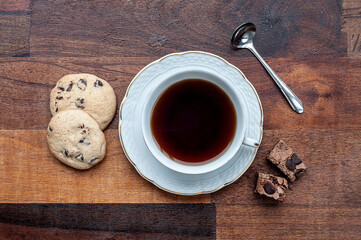 Five o'clock tea served in a white cup, with a spoon and cookies.