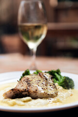 Chicken dish with cream and broccoli and a glass of white wine. Italian fine dinning