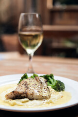 Chicken dish with cream and broccoli and a glass of white wine. Italian fine dinning