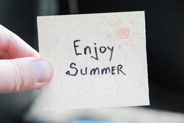 Enjoy summer. Creative concept. Hand holding a tag with the inscription.