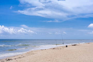 Surf Fishing two rods in the sand on coastline with white beach chair for lounging and relaxing on...