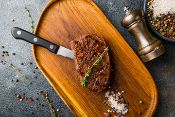 roast beef Steak with salt and pepper on the board on dark stone table