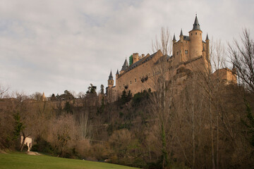 Views of the Alcazar of Segovia with the deciduous trees at the base of the cliff