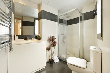 Bathroom with white wood cabinets, frameless mirror, white slippers, and single stall shower
