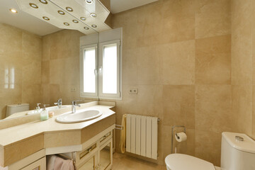 Bathroom with cream marble sink, large frameless wall mirror and unlit halogen lamps