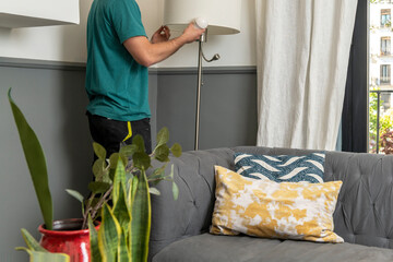Operator changing a light bulb in a lamp in the living room of a house