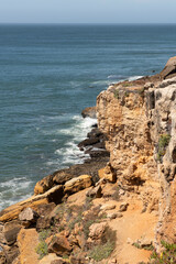 Nice brownstone cliffs on the Portuguese Atlantic coast on a warm summer day with the breeze on the rocks near the sea whipping the rocks