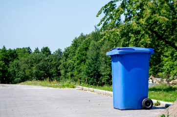 Unloocked big empty blue plastic trash garbage bin