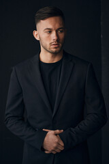 Modelling snapshots. Narcissistic self-confident tanned attractive handsome man in classic suit jacket looks aside posing isolated in over black studio background. Fashion offer. Copy space for ad