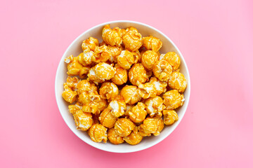 Honey caramel popcorn on pink background.