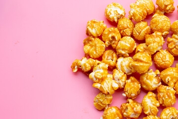 Honey caramel popcorn on pink background.