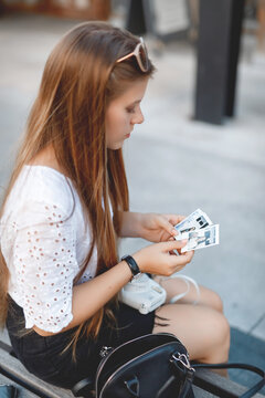 young girl sitting and looking at photos with a polaroid