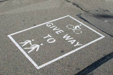 Warning sign for a bicycle rider to give way to pedestrians has shown on the road.
