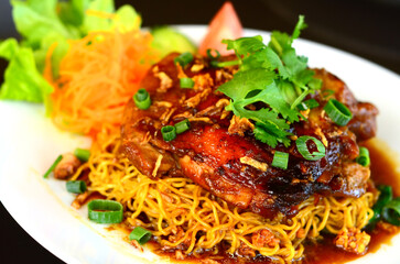 A roasted chicken with egg noodles isolated on black background.