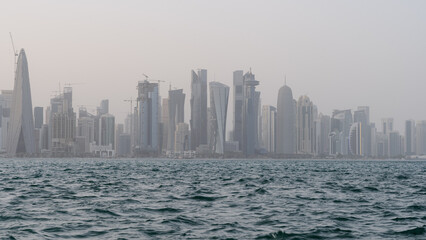Obraz premium Qatar skyline with rough sea in the foreground on a windy and rainy day.