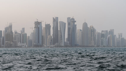 Obraz premium Qatar skyline with rough sea in the foreground on a windy and rainy day.