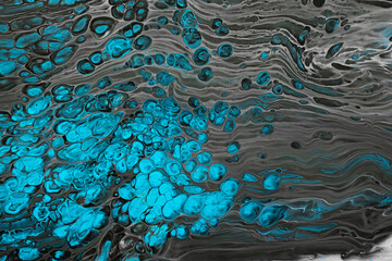 Fluid Art. Abstract mixing black waves and turquoise bubbles. Liquid flows splashes. Marble effect background or texture