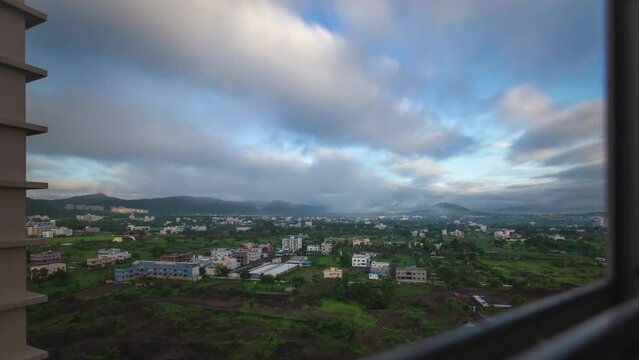 Time clouds over the city, window view from high-rise building. Monsoon morning in Pune, India.
