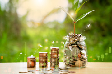Stacking coins in a jar with grow up on wooden , nature background for financial investment and...