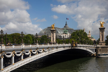 The famous Alexander III Bridge over the Seine River in Paris is the most beautiful bridge in the city and is located next to the Eiffel Tower which attracts tourists and travelers.