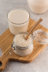  A jar of raw rice and rice milk in a glass on a plank. Healthy food concept, alternative milk.