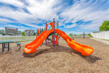 Orange slides in a small playground with picnic table and picket fence at Utah Valley