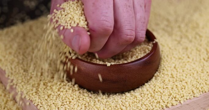 Take a bowl of raw cereal porridge couscous from wheat or millet, cooking dishes from traditional cereals crushed yellow couscous