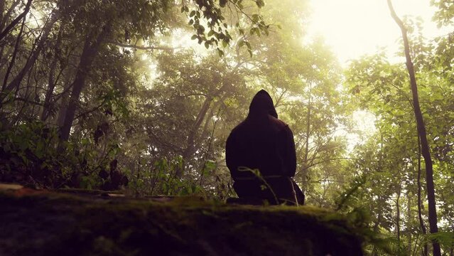 Monje fraile franciscano religioso católico, cristiano meditando o rezando sentado contemplando la naturaleza en el bosque