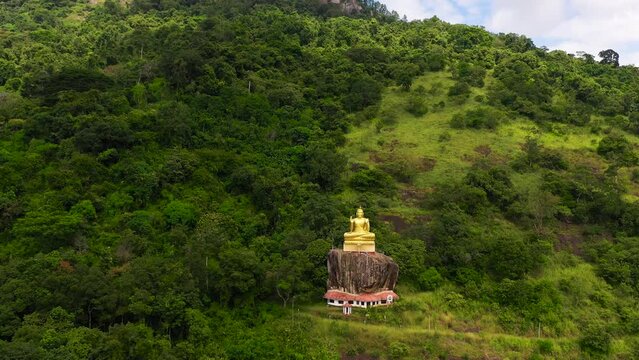 A statue of the golden Buddha in a mountain Buddhist temple. Aluvihara Rock Temple, Matale, Central Province, Sri Lanka