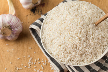  Raw round white rice in a bowl close-up on a wooden background. Healthy food.