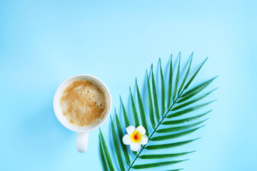 Milk coffee with plumeria flowers and palm leaves on blue. Cozy vocational morning. Coffee break. Relaxing atmosphere. Eco life. Summer style. Hotel room service. Exotic countries.